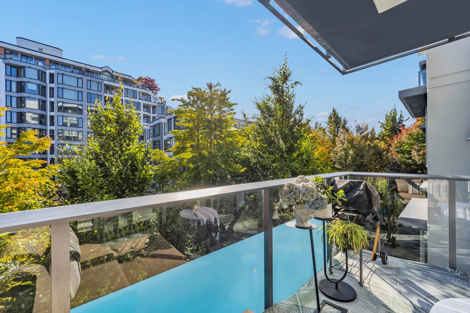 Along the balcony: the glass railing, the neighbouring balconies, the trees below