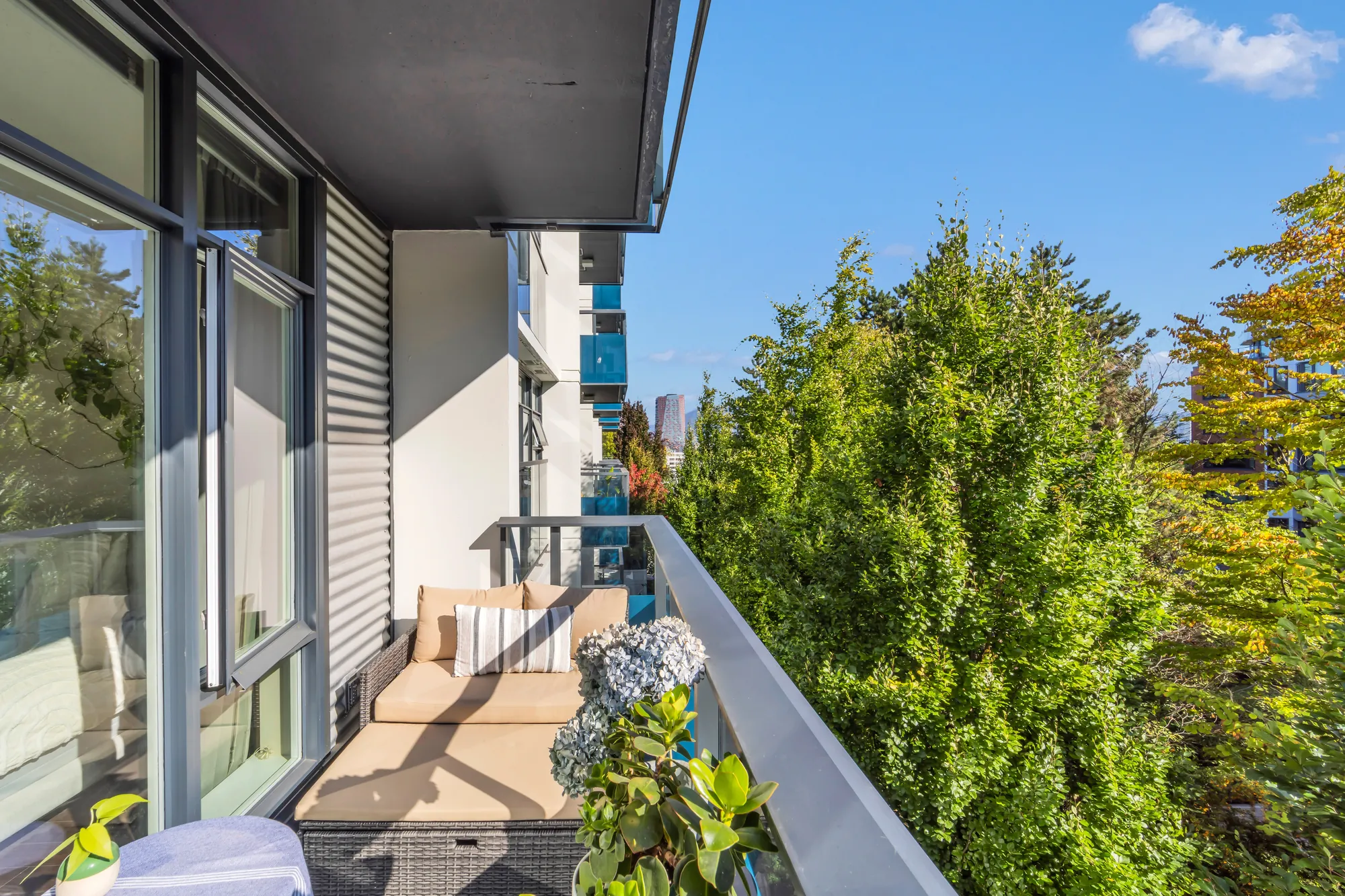 The balcony from its end: the sofa, the door to the living room, the trees