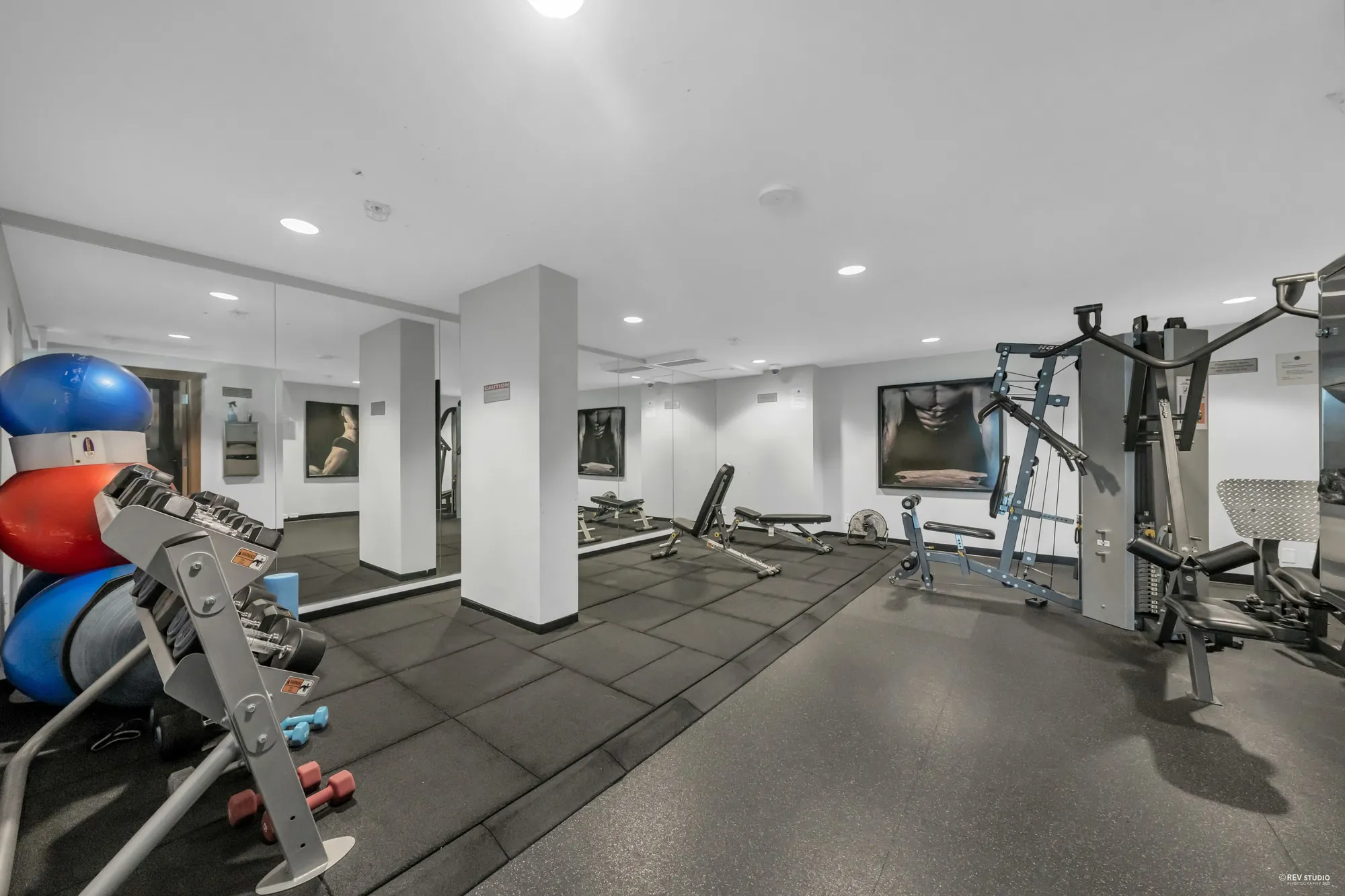 The exercise room: weight machines, a rack of balls and dumbbells, a rubber floor
