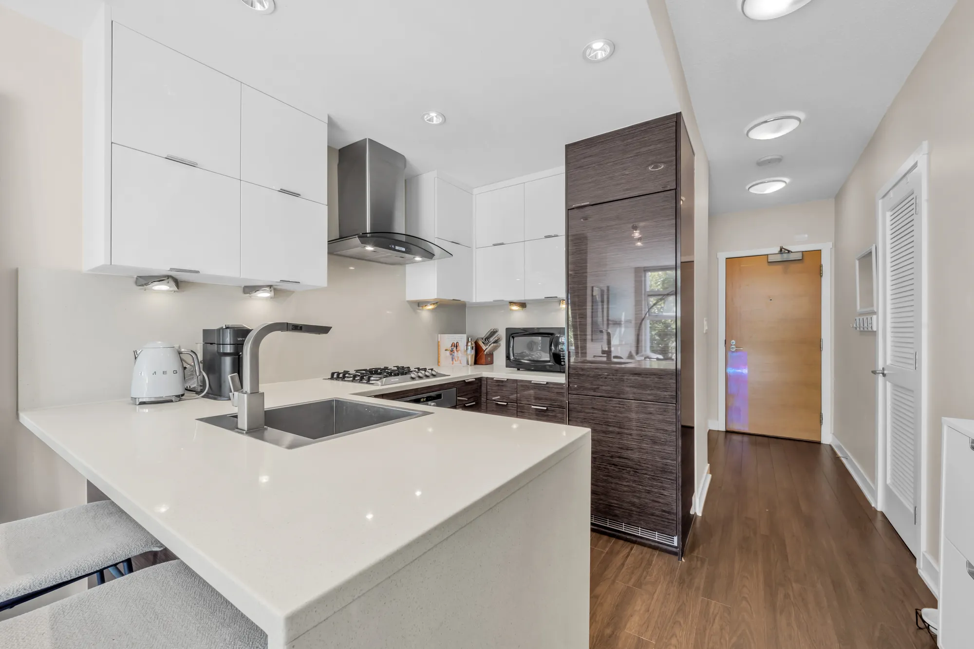 The kitchen toward the front door: the peninsula, the tall cabinet with the integrated refrigerator, the foyer and the door