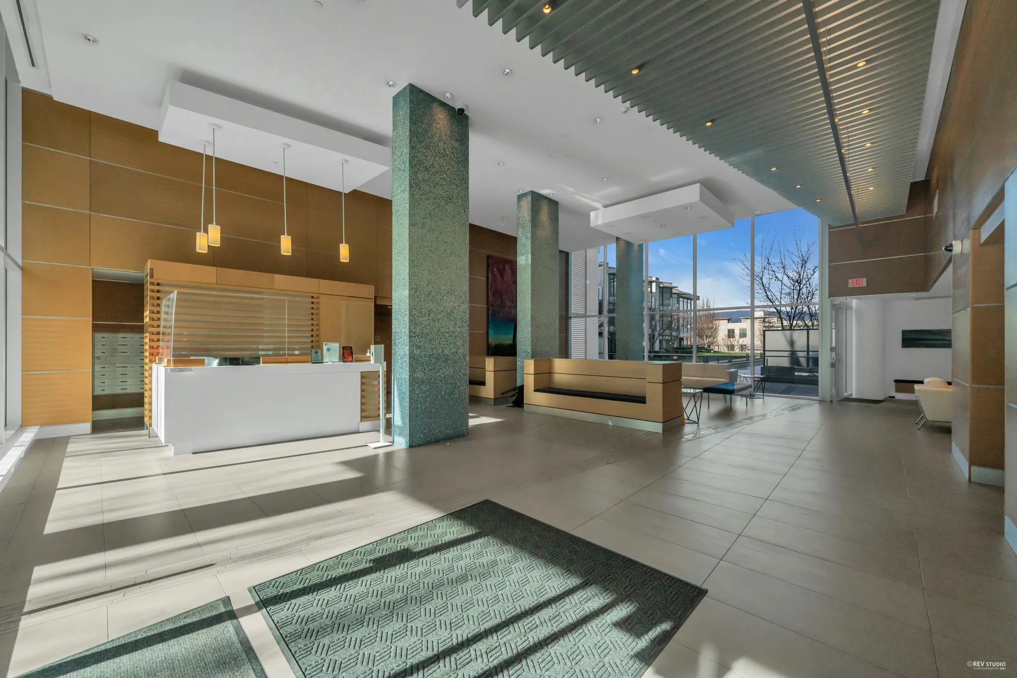The lobby toward the concierge desk: pendant lights, wood panelling, the glass wall to the street