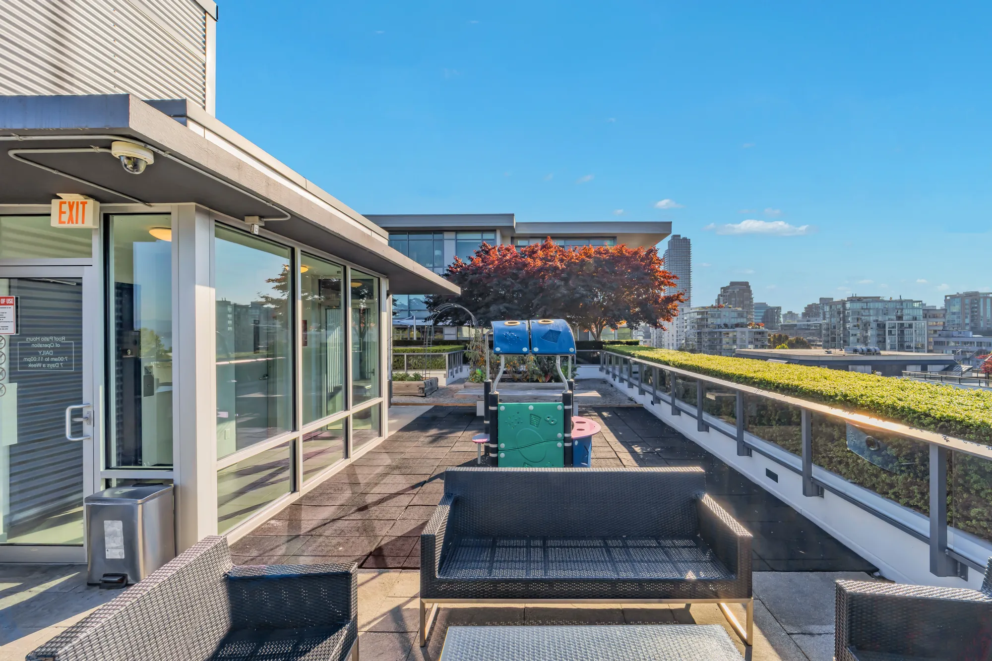 The rooftop lounge: sofas on a deck beside a glass pavilion, planters, the city beyond
